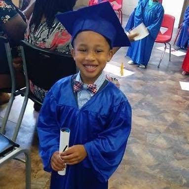 Child in blue graduation cap and gown holding a diploma