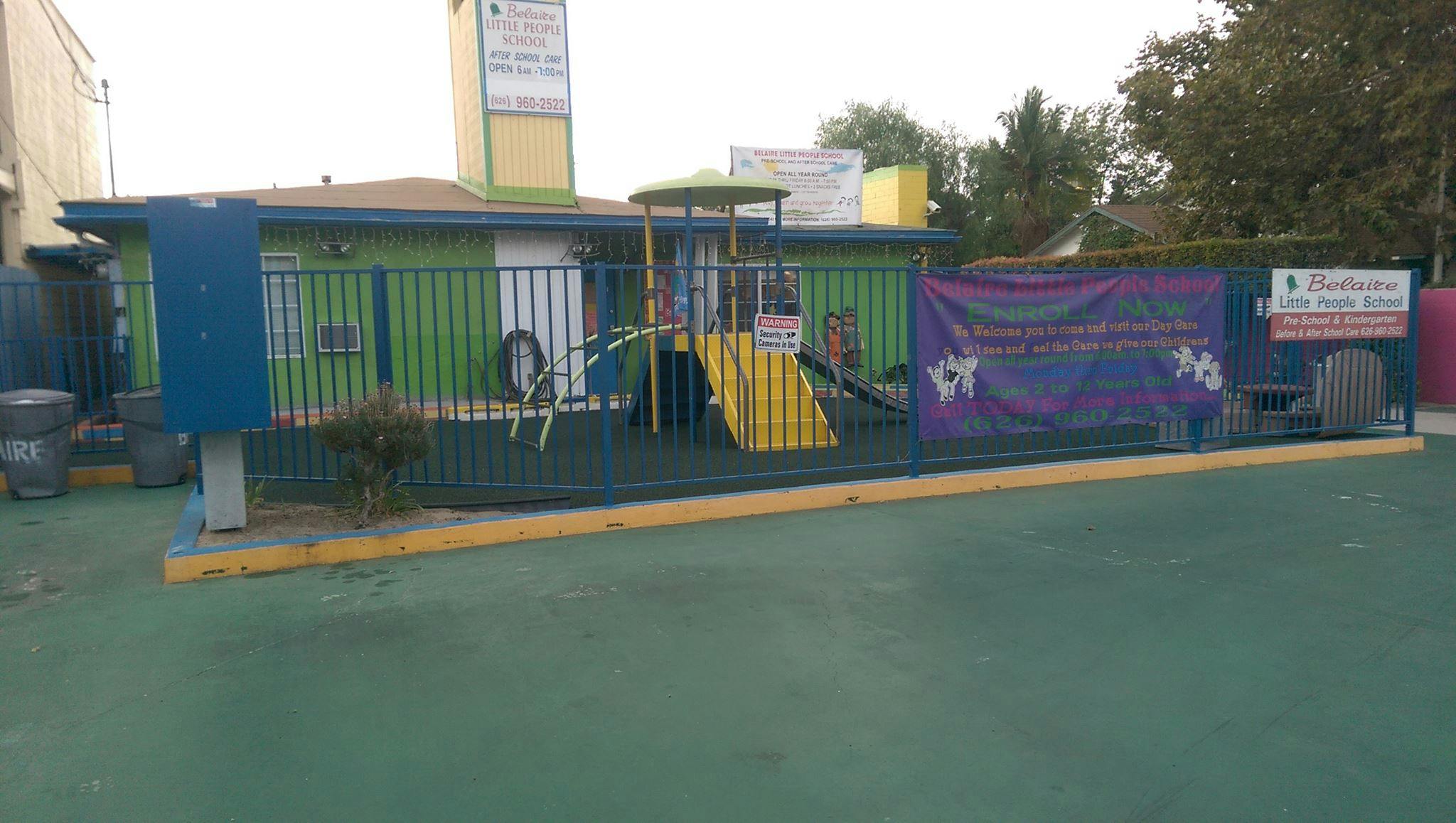 Playground with a slide and a building behind a fence