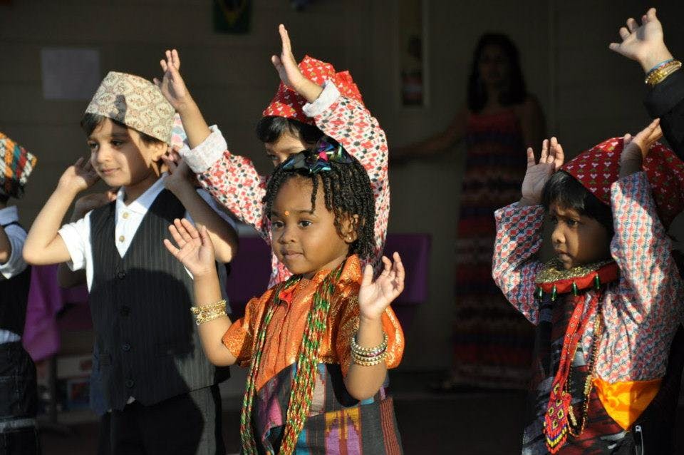 Children in traditional clothing raising their hands