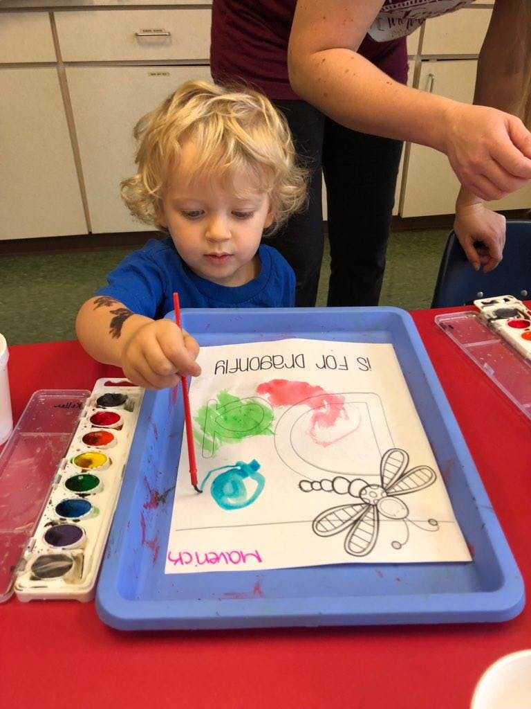 Child painting a picture of a dragonfly with watercolors