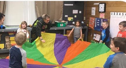 Adult and children playing with a colorful parachute