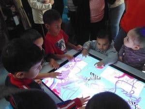 Children interacting with a large illuminated screen