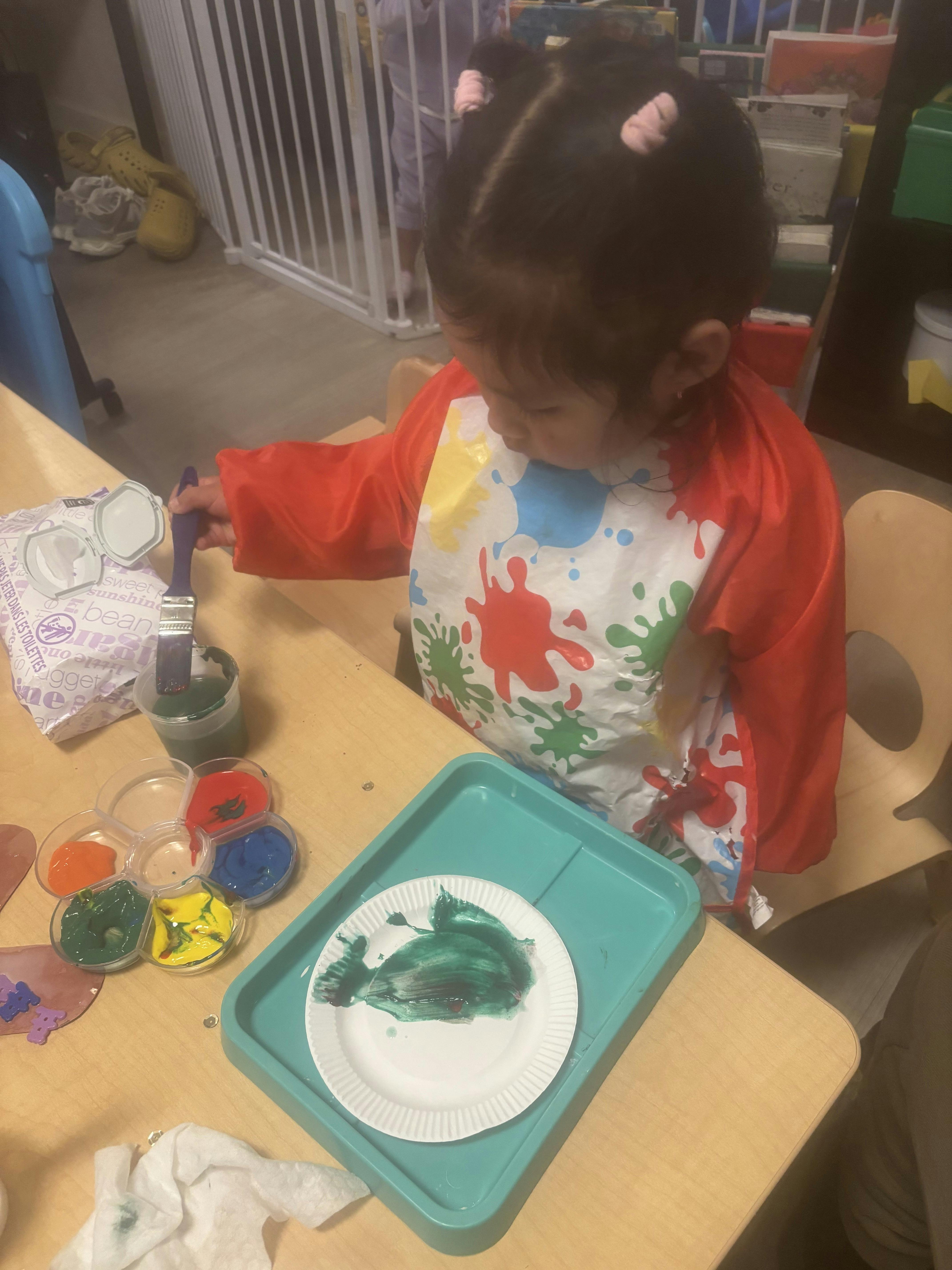 Child painting on a paper plate at a table