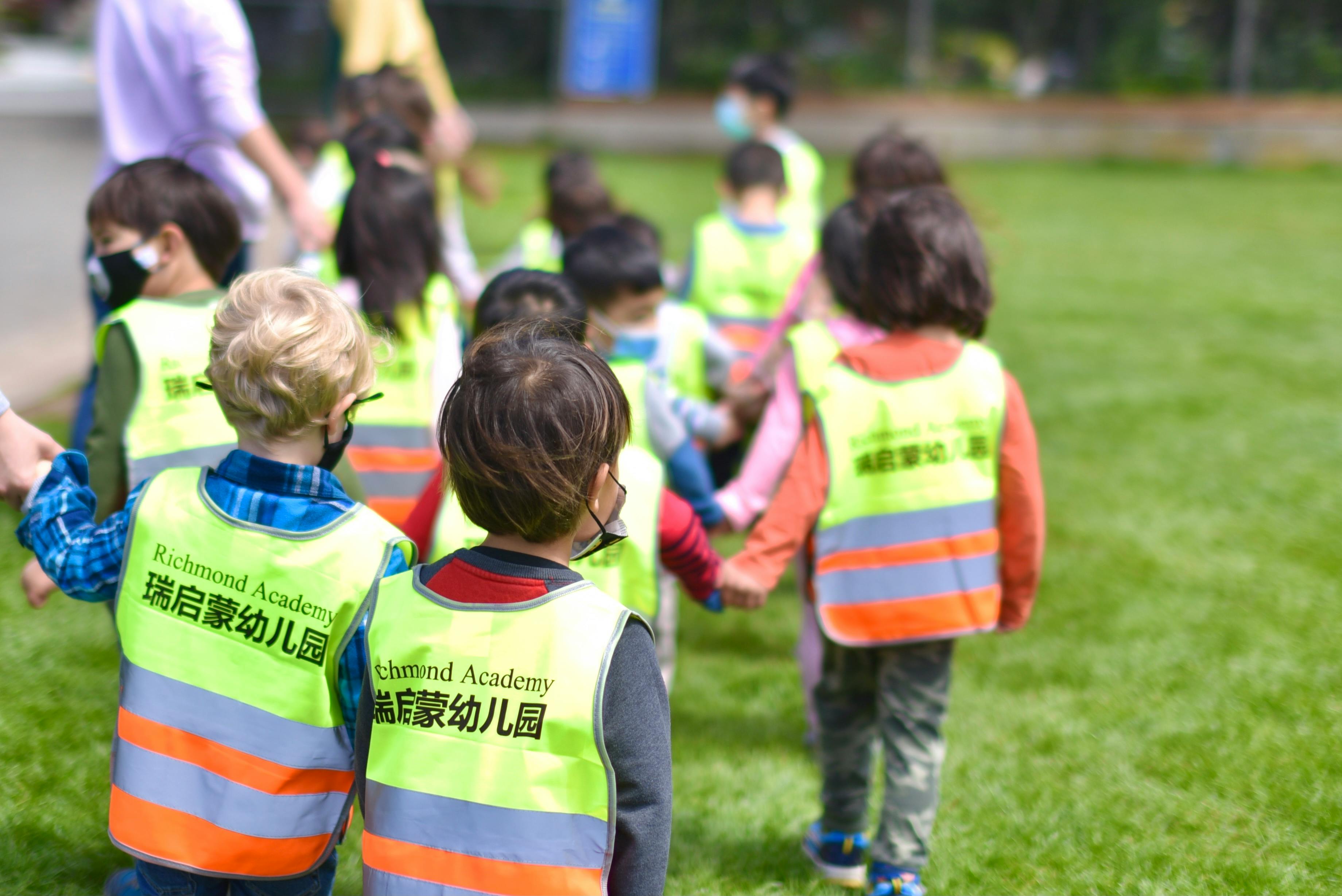 Children in safety vests walking on grass