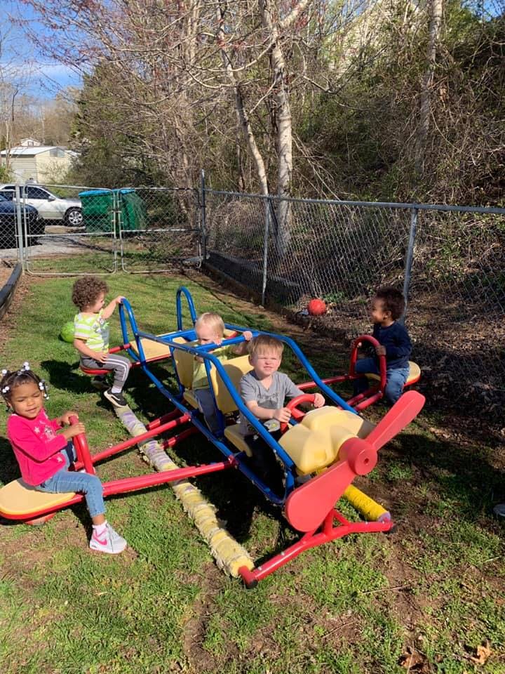 Children playing on a seesaw and a spring rider in a playground