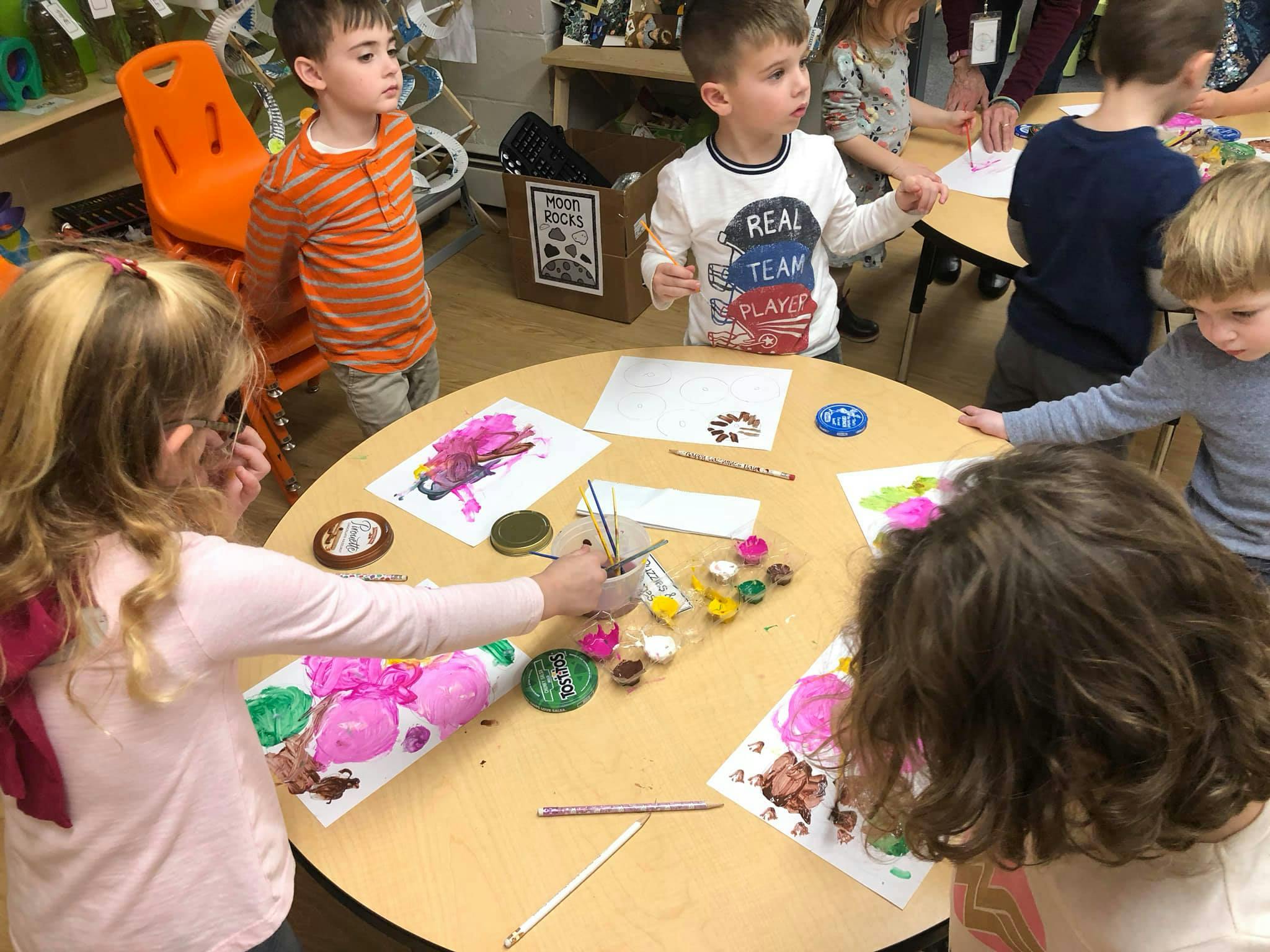 Children painting at a round table in a classroom