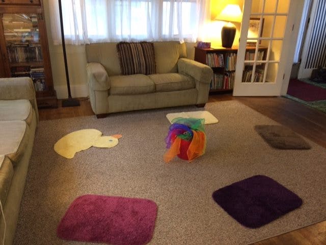 Living room with a sofa, colorful play items, and small mats on the carpet