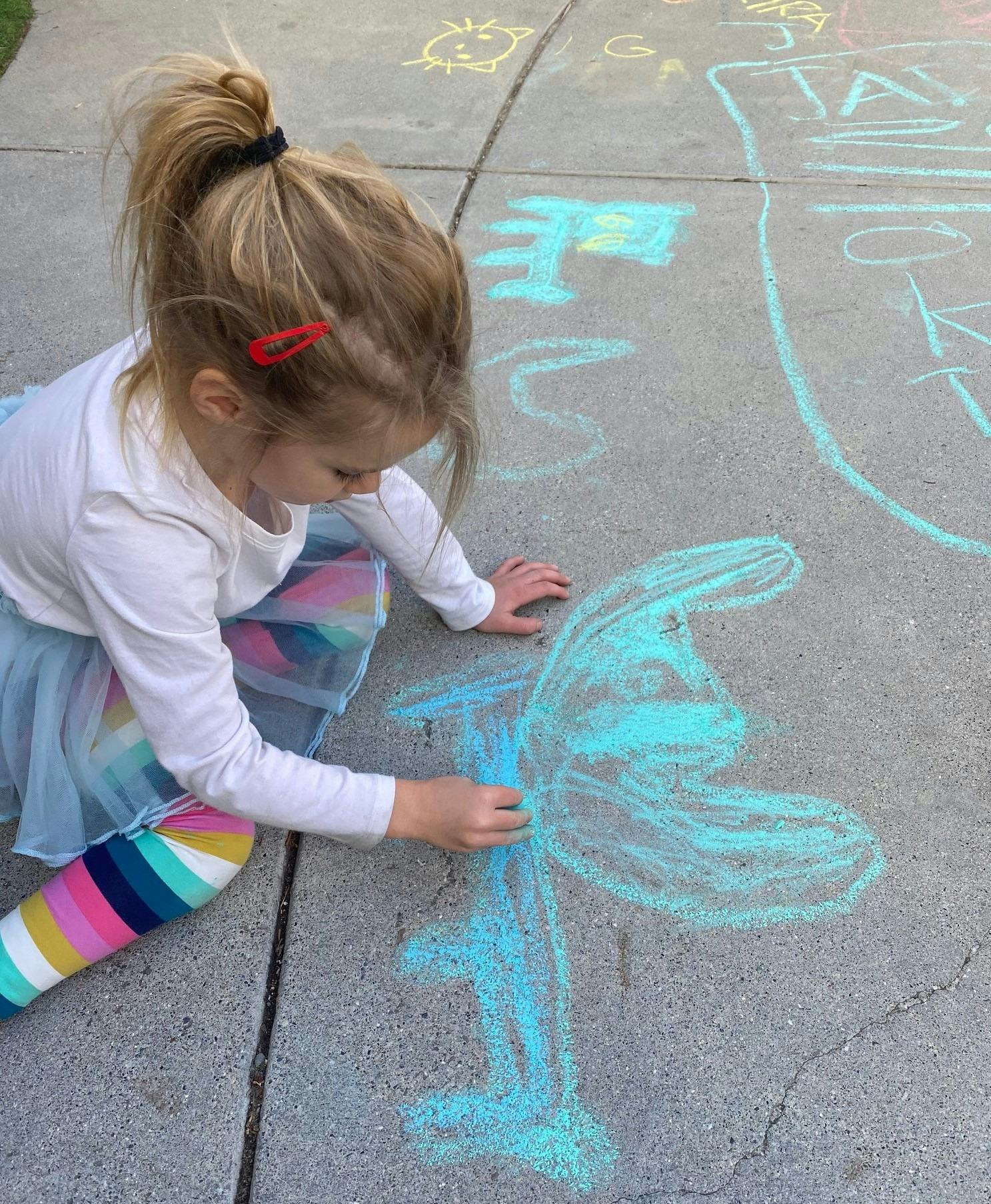 Child drawing with chalk on pavement