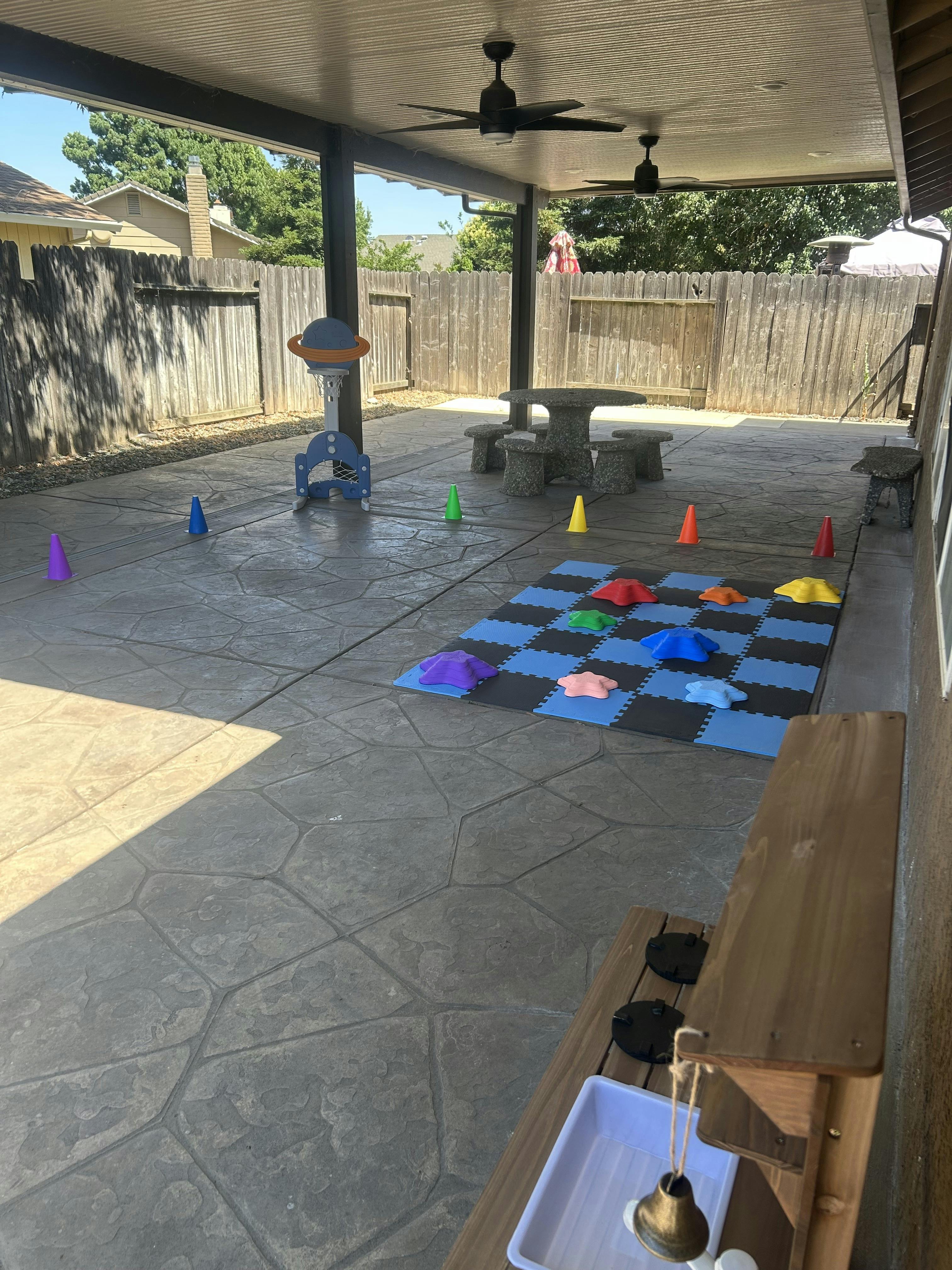 Outdoor patio with play equipment, cones, and a checkerboard mat