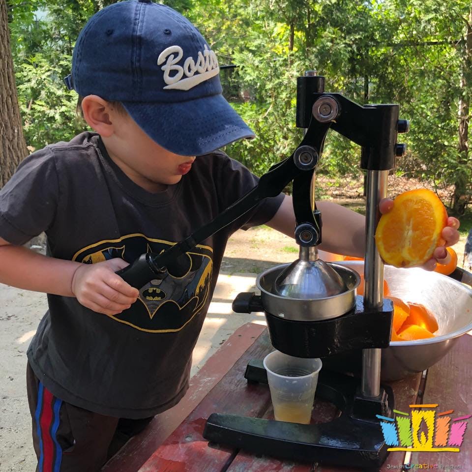 Child using a manual juicer to press an orange