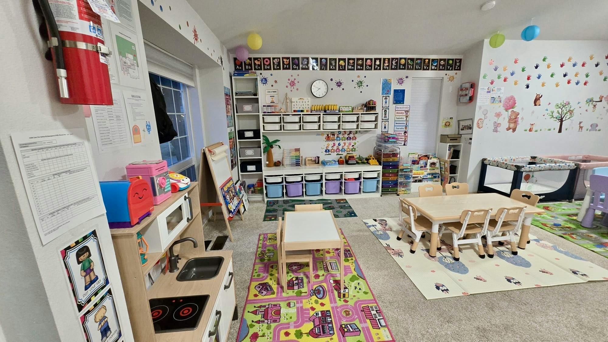 Childcare classroom with small tables chairs toy kitchen and educational wall decor