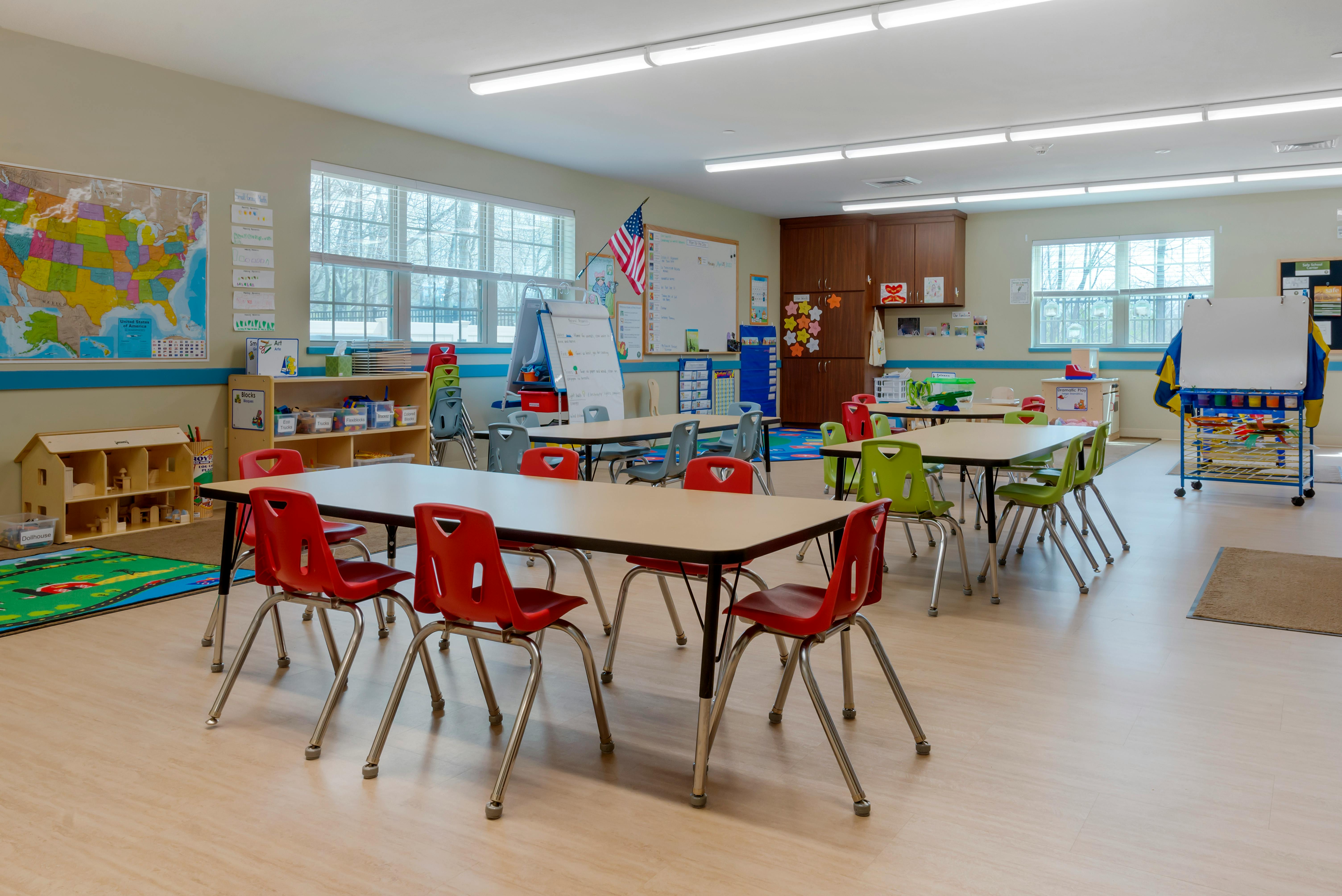An empty classroom with several tables and chairs for young children