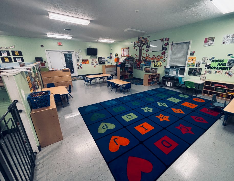 Colorful preschool classroom with tables and alphabet rug