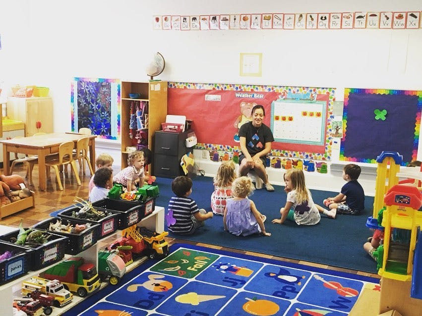 Adult and children sitting on a rug in a classroom