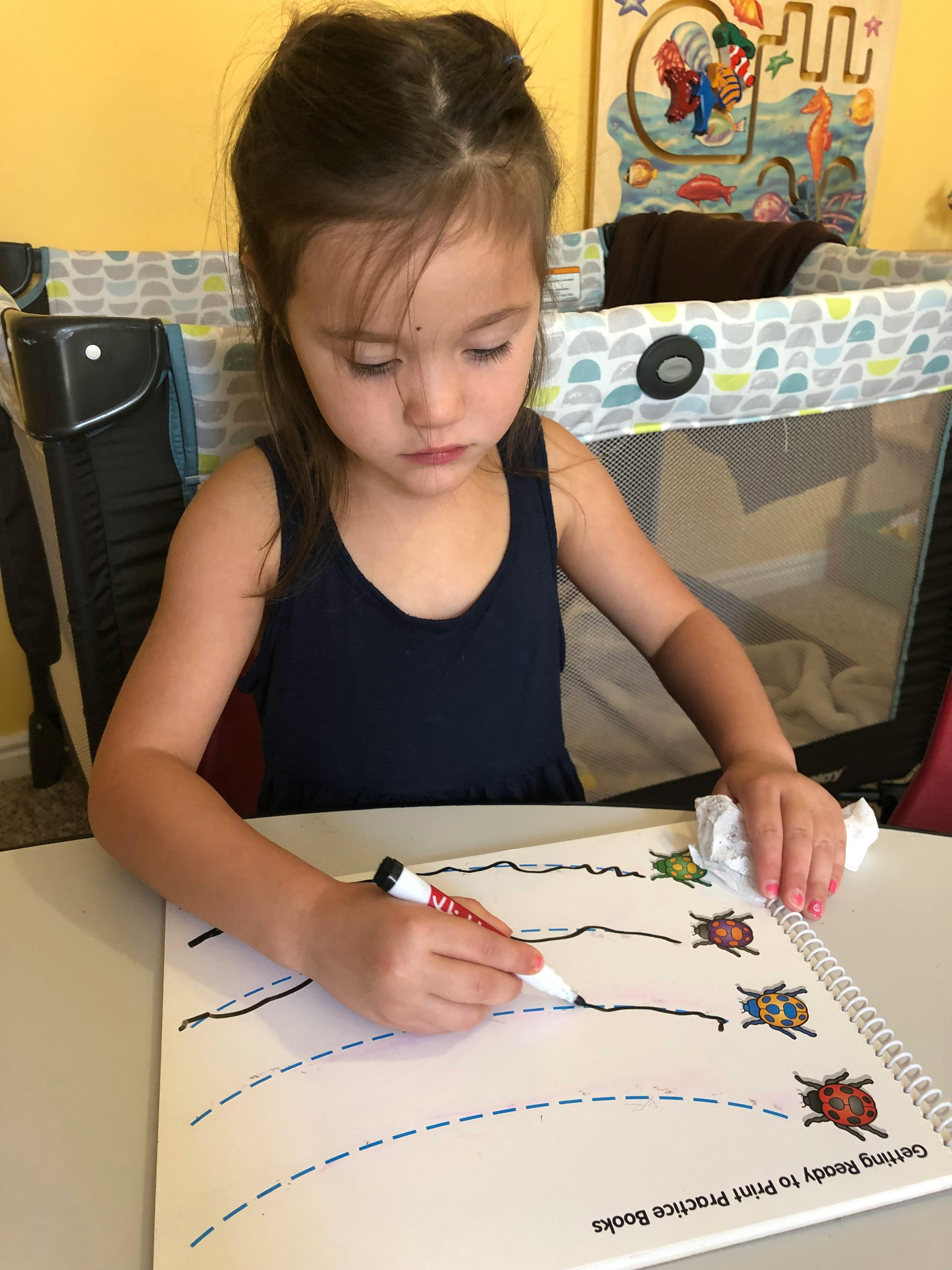 Child drawing on a practice book with a marker