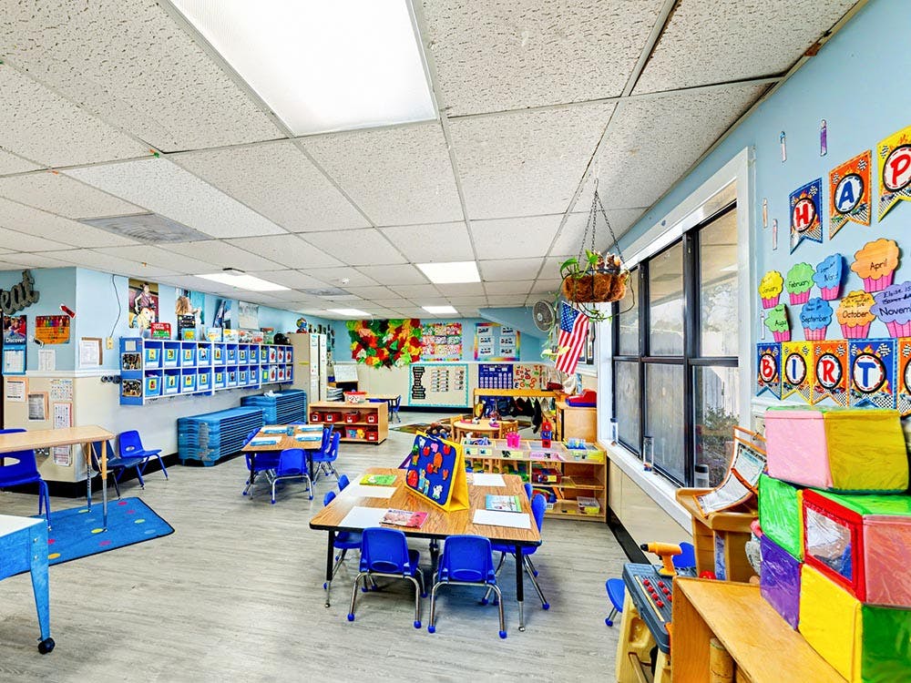 Colorful empty classroom with small tables and chairs arranged