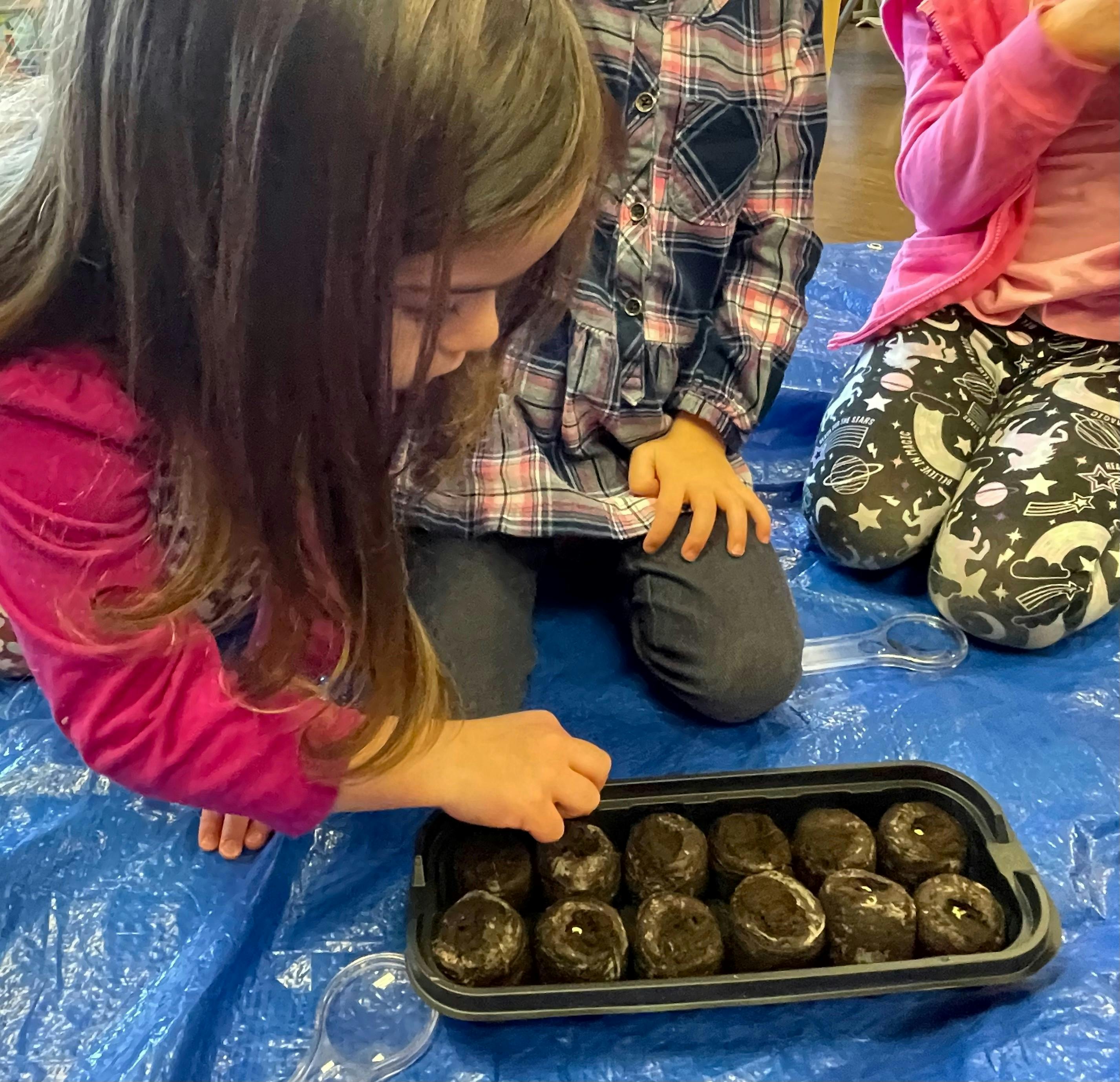 Child planting seeds in a tray