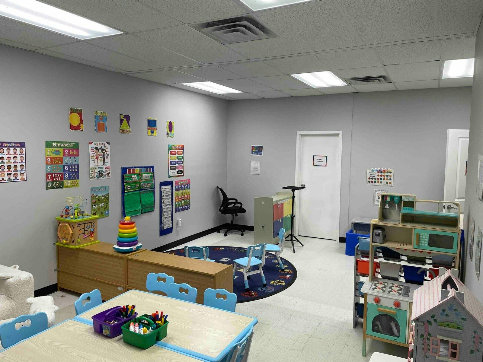 A classroom with activity tables, chairs, and learning posters on the walls
