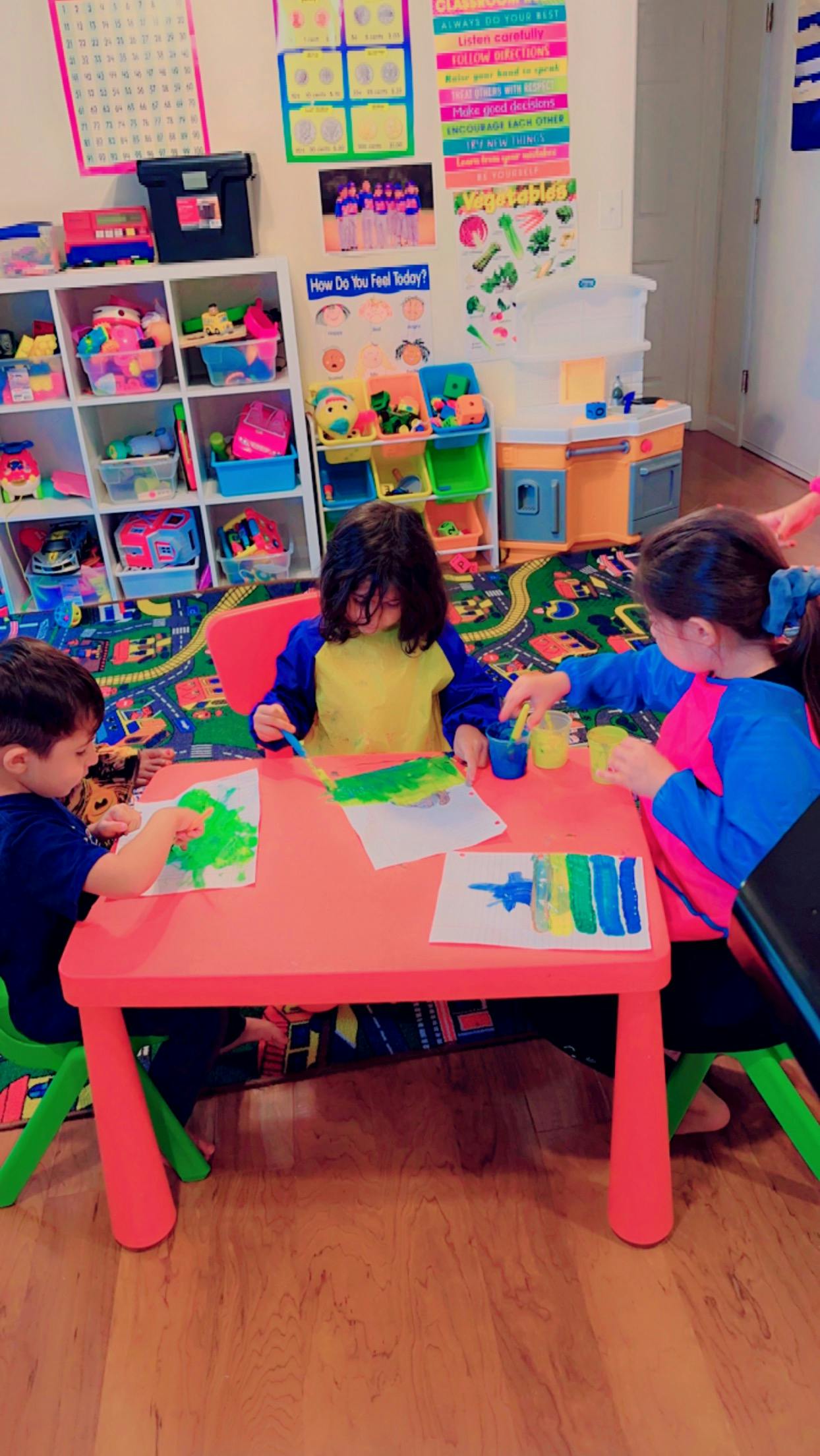 Three children painting at a small table in a classroom