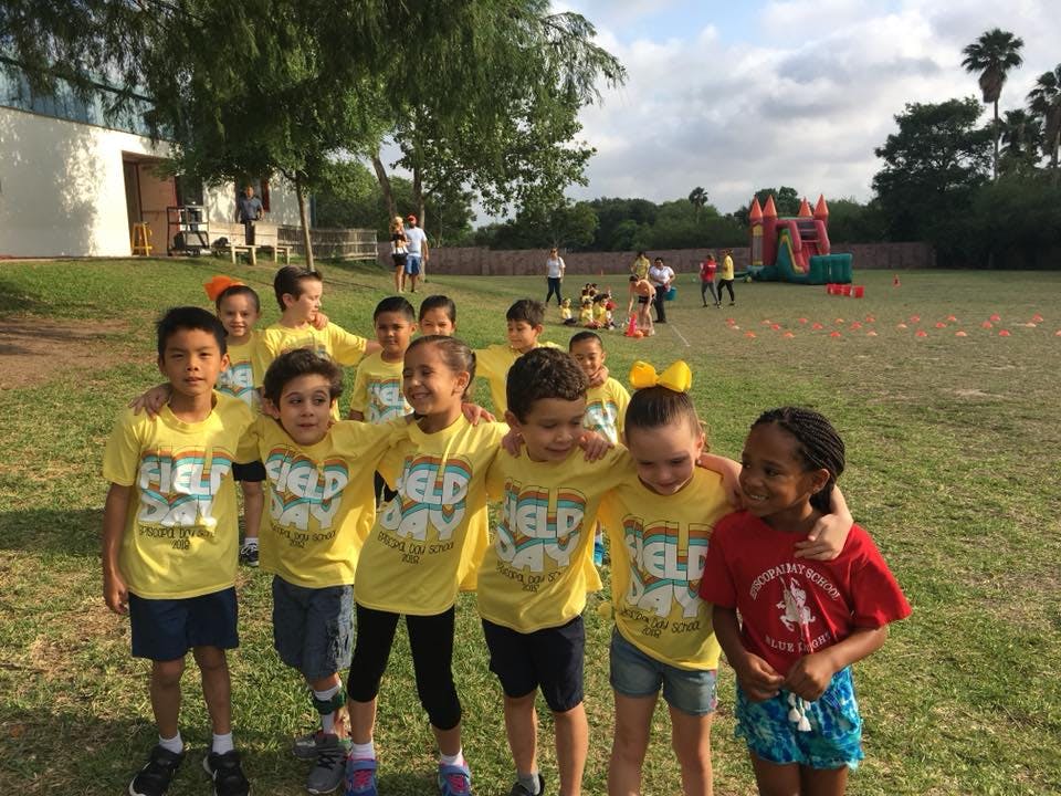Group of children in yellow shirts with "Field Day" text on a grassy field