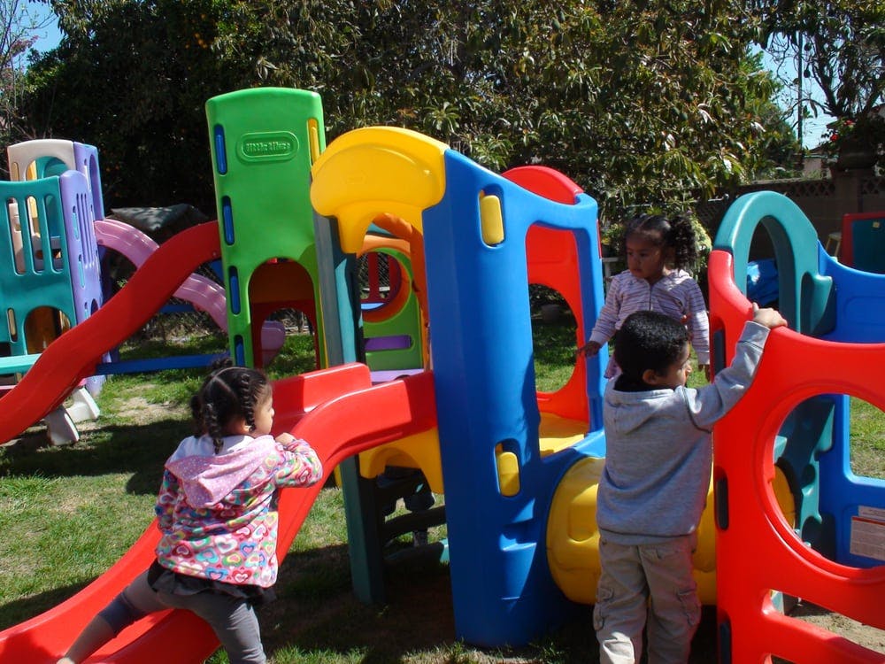 Three children playing on a colorful playground structure