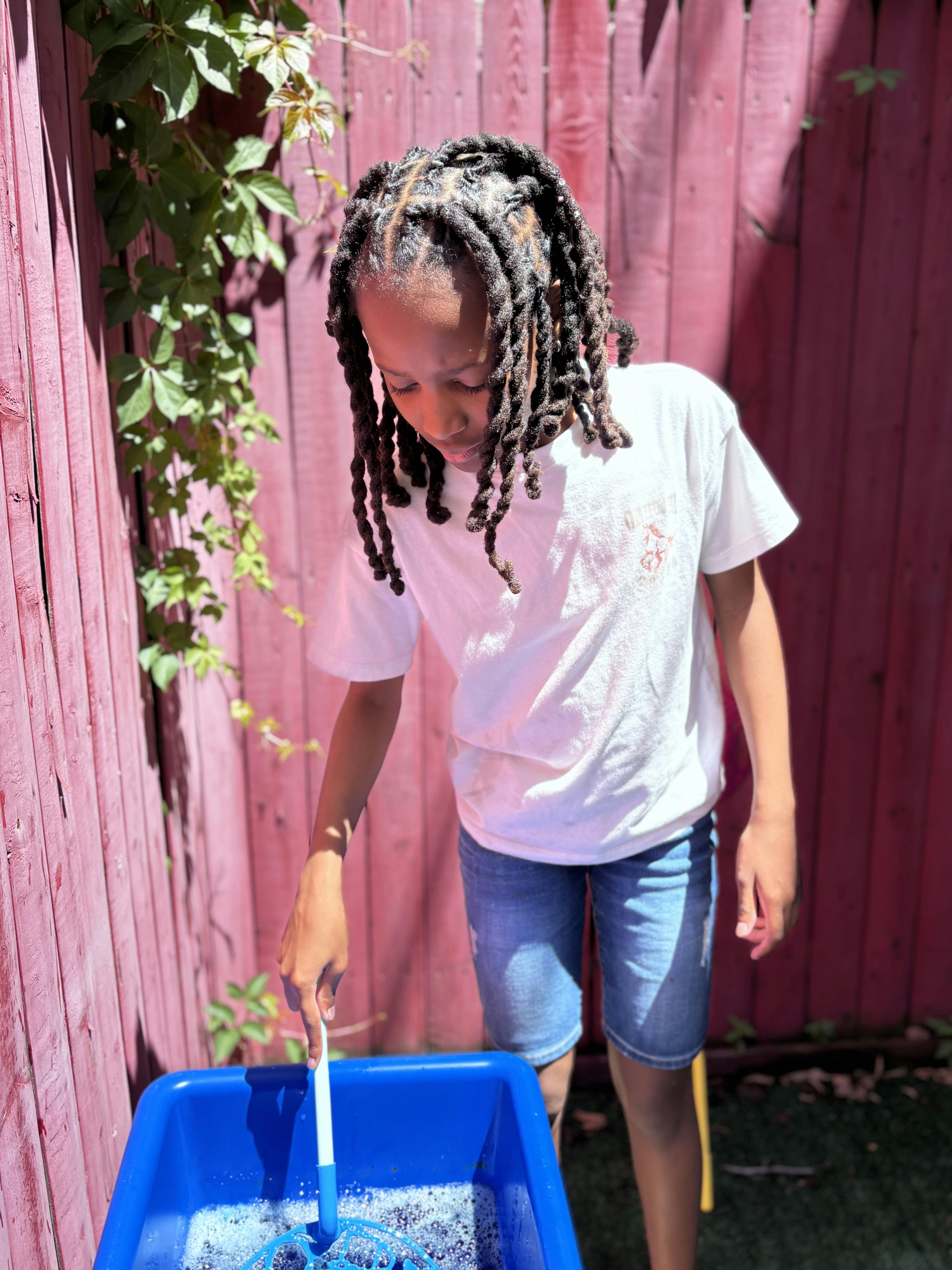Child playing with bubbles in a blue container