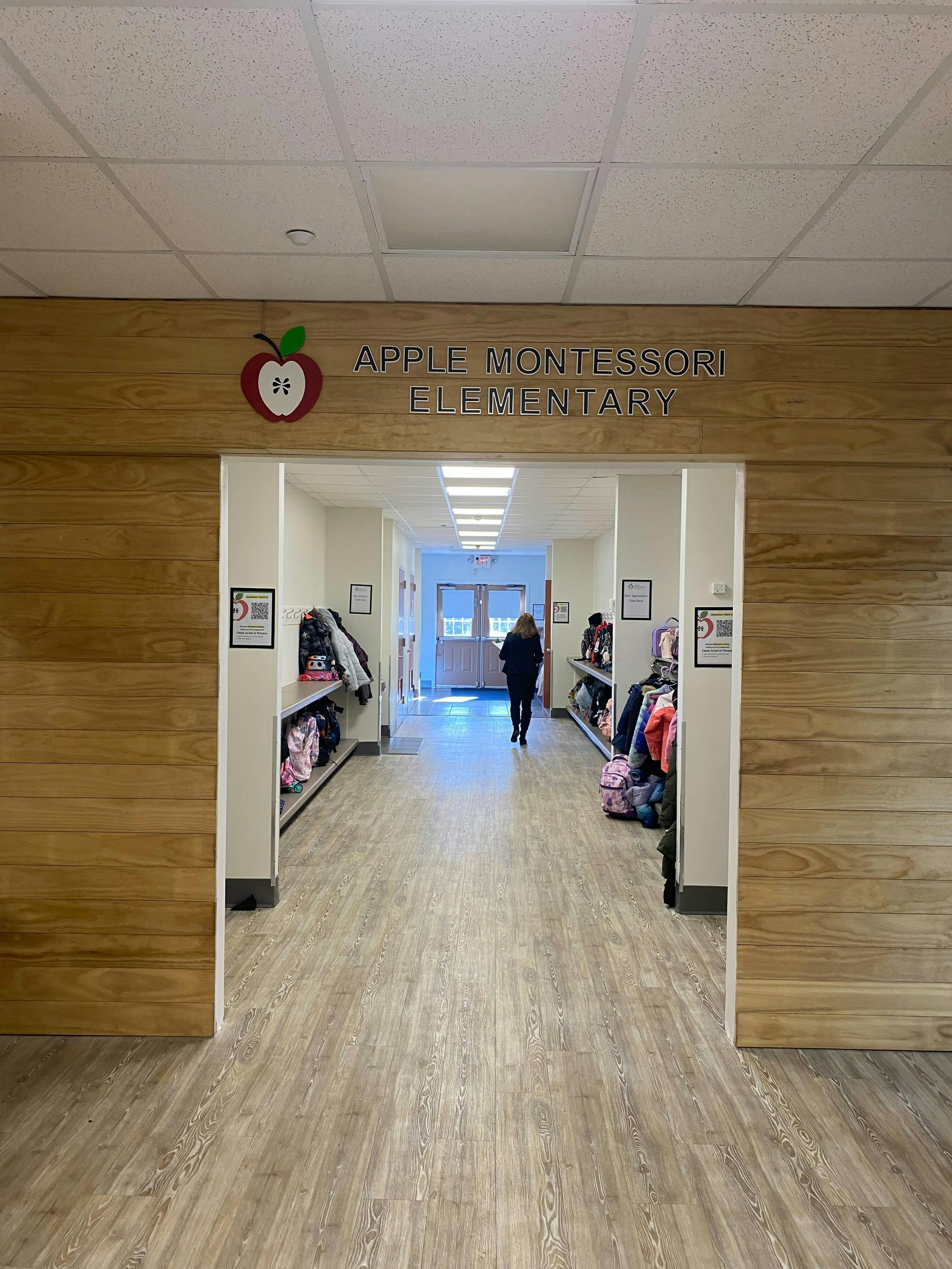 Sign for Apple Montessori Elementary above a person walking down a hallway