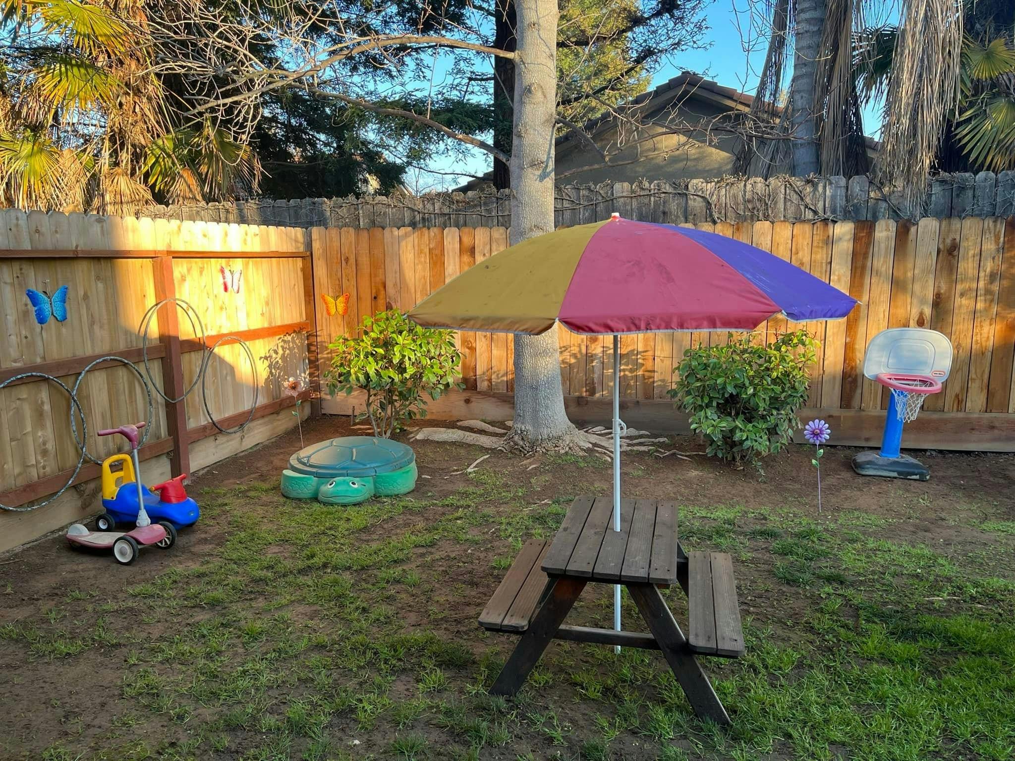 Backyard with a picnic table, umbrella, and children's toys