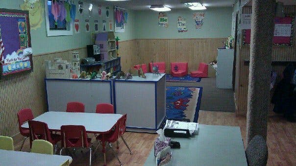 Classroom with small tables and chairs, and a play area