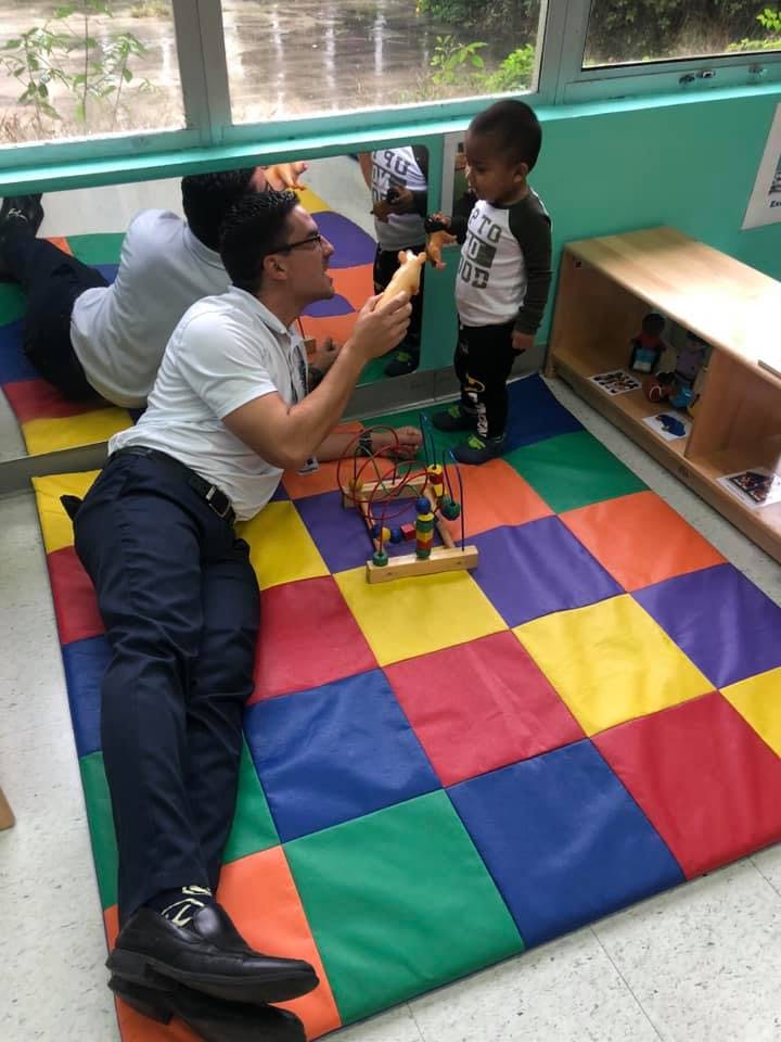 Person on floor playing with child in a classroom
