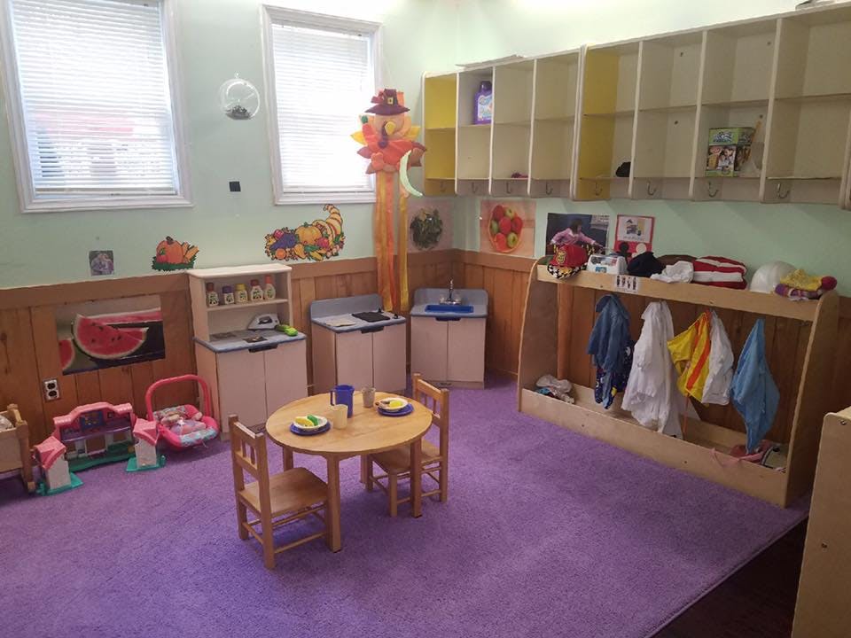 Children's play area with small table and chairs, play kitchen, and coat rack