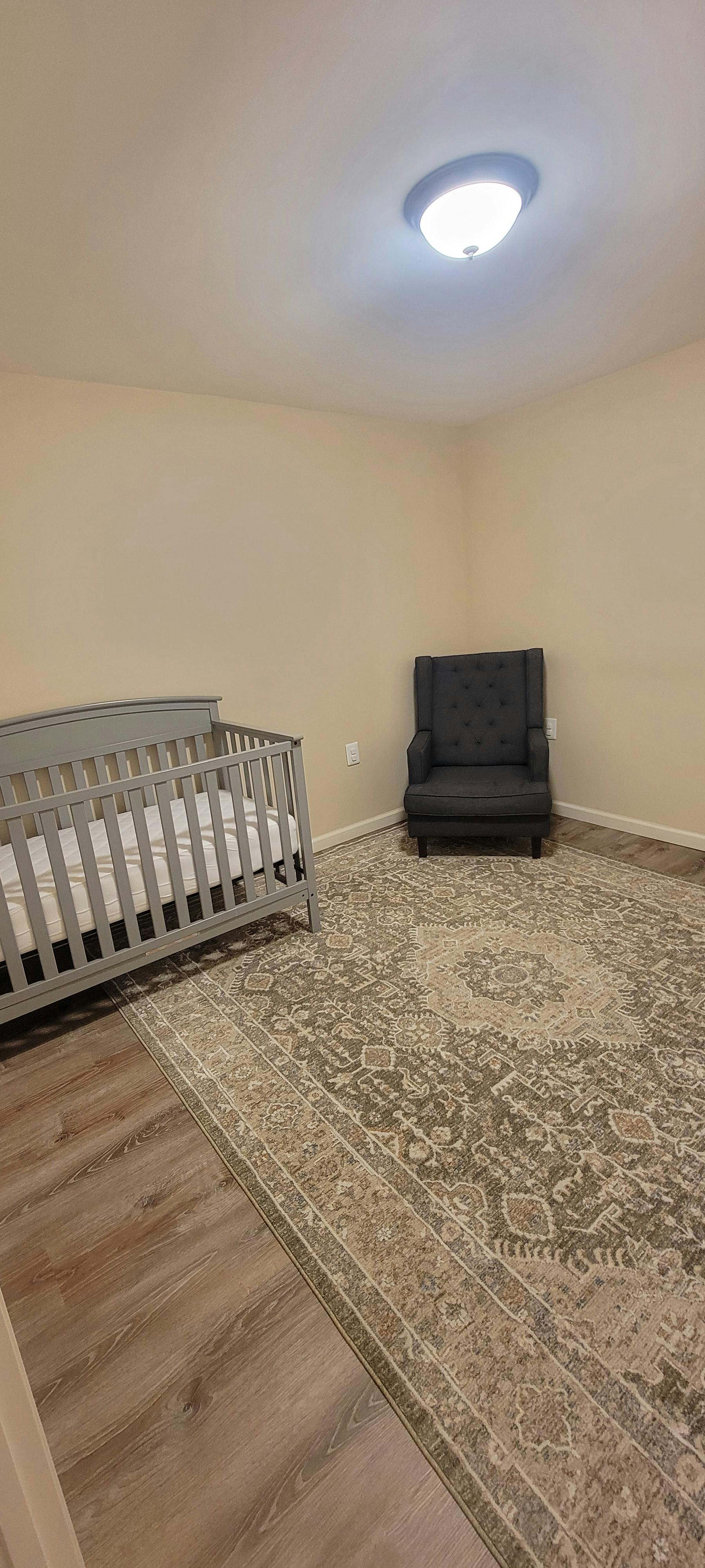 Crib and armchair in a nursery with an area rug
