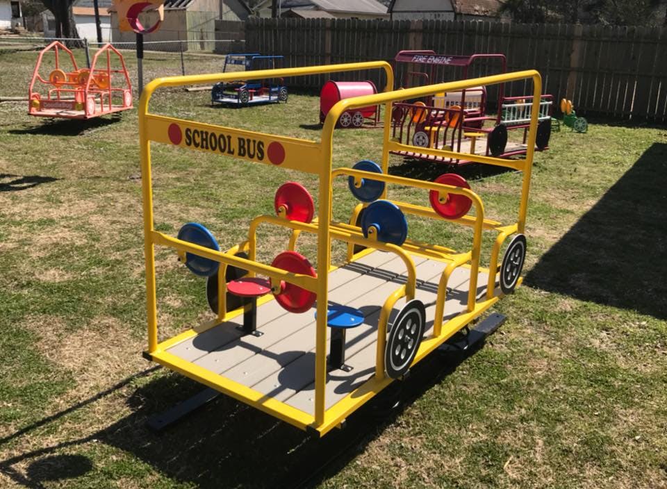 Yellow school bus playground equipment with red and blue seats