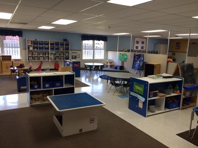 empty classroom with tables, chairs, and cubbies