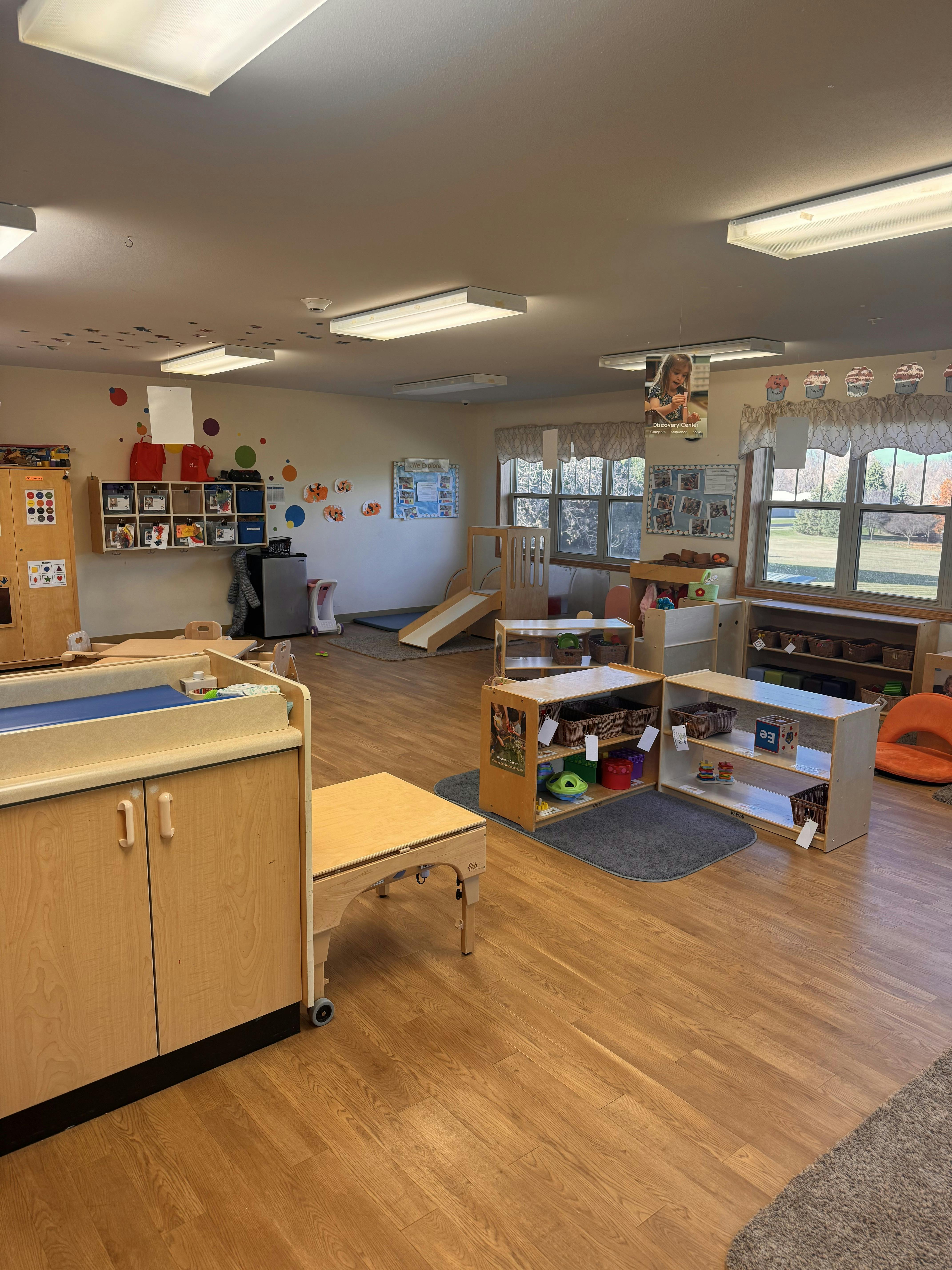 Empty classroom with light wood furniture, toys, and bulletin boards