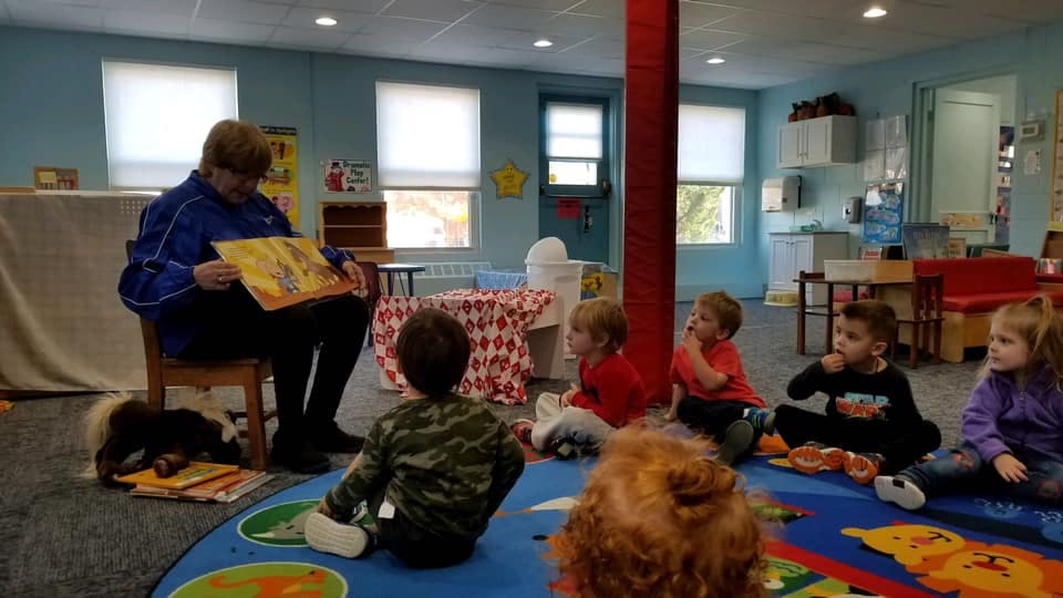 Person reading a book to children sitting on the floor
