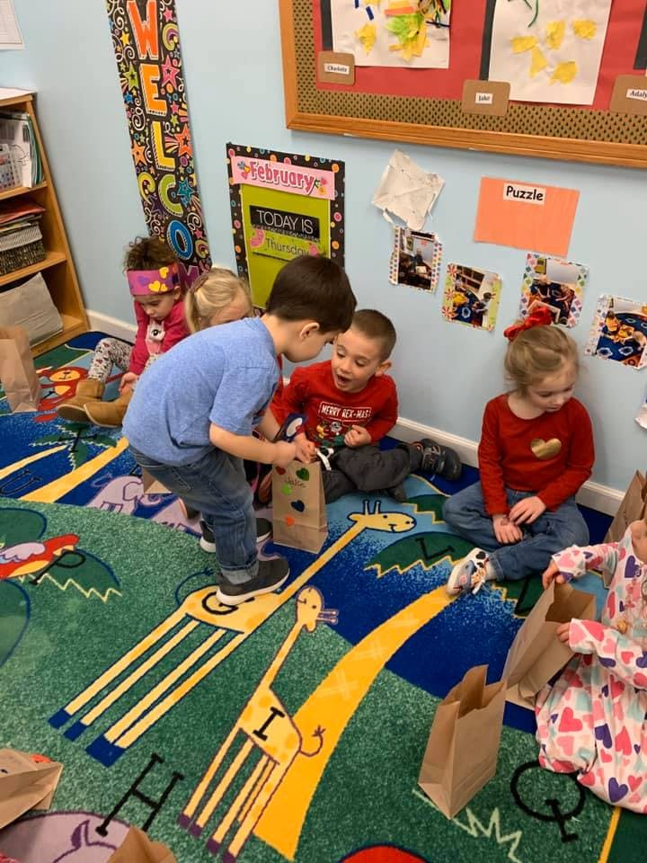 Children in a classroom looking at items in paper bags