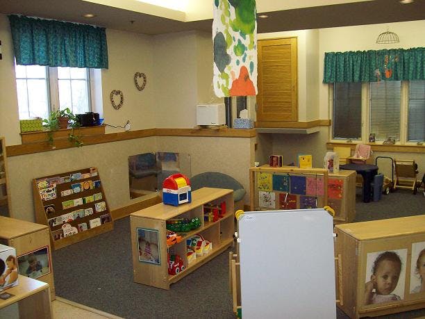 Playroom with shelves of toys and books, windows with teal valances