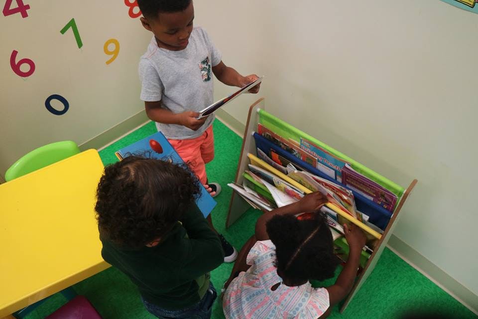 Three children looking at books in a classroom