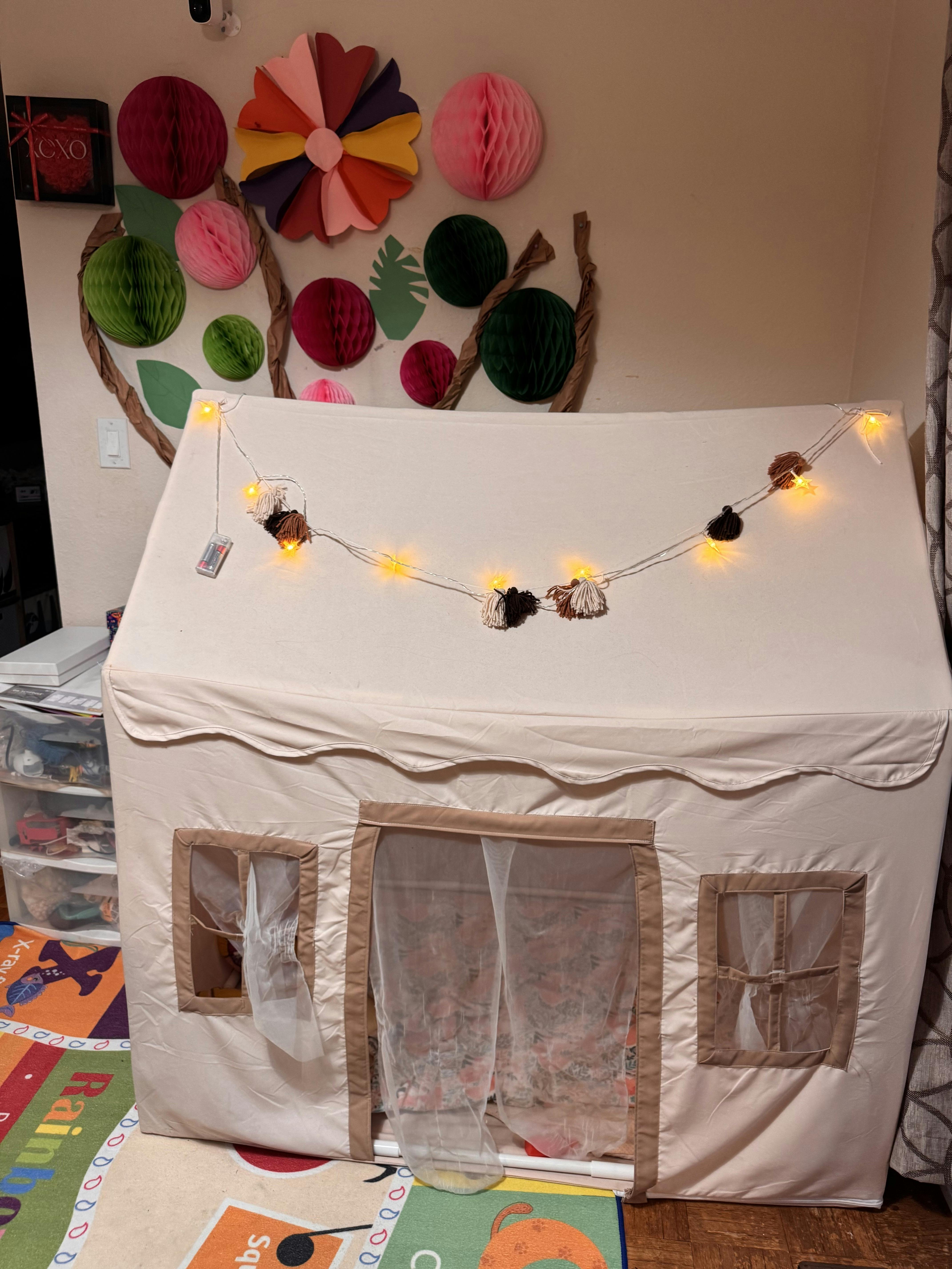 Cream colored fabric play tent decorated with string lights