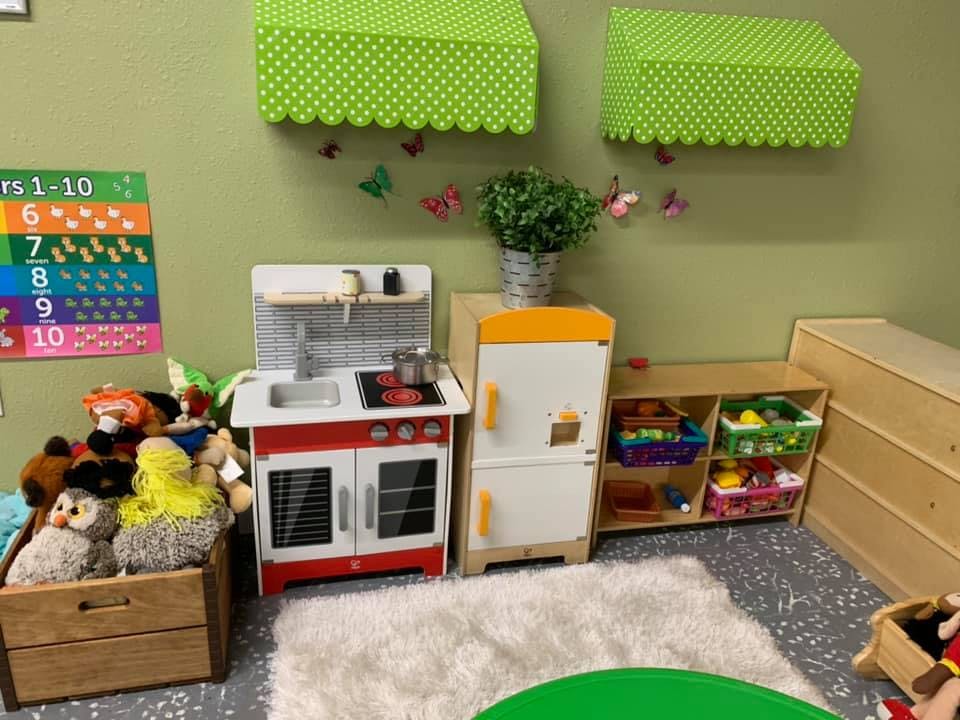 Toy kitchen set with a stove, sink, and refrigerator in a classroom