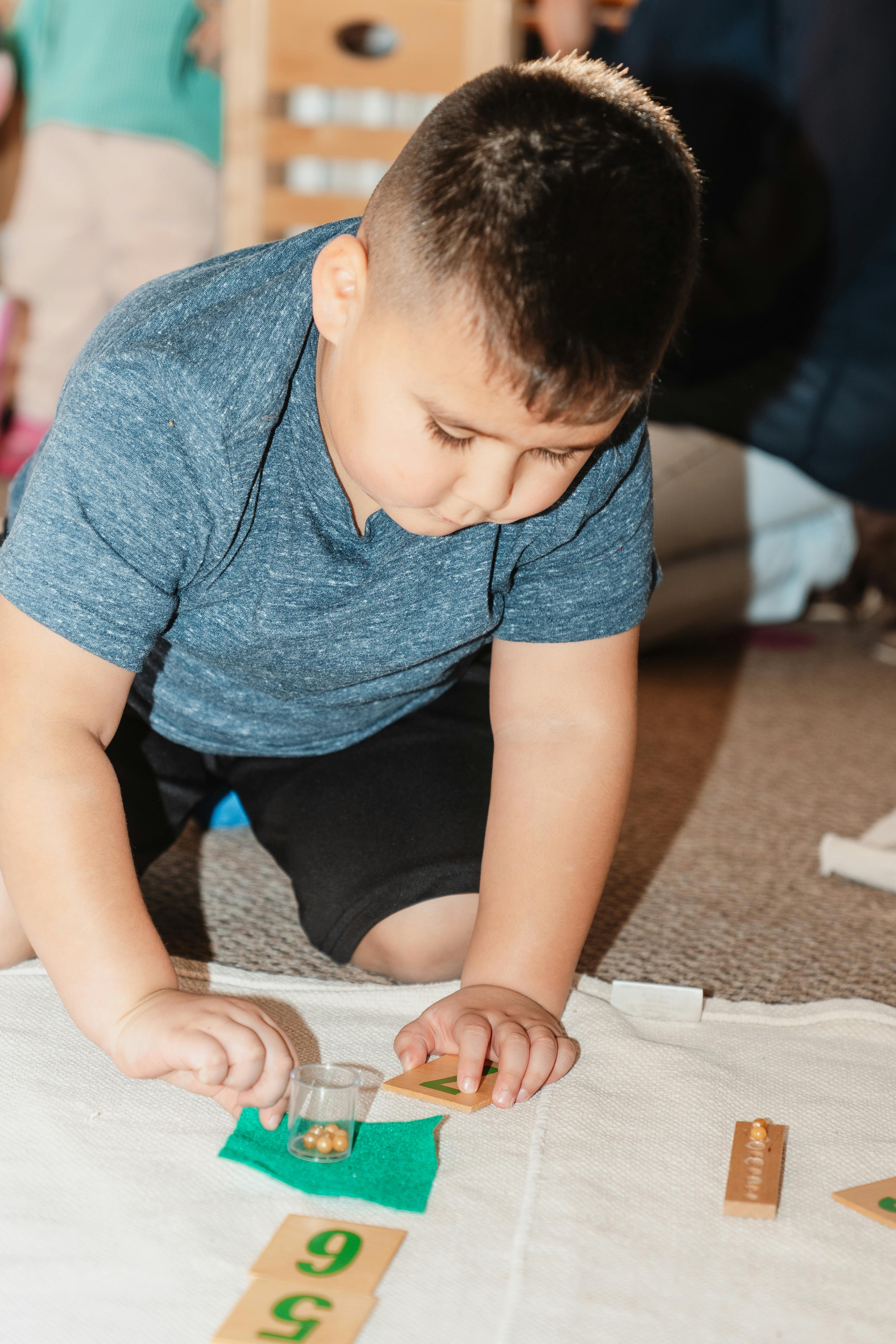 Child kneeling and playing with number blocks and small beads