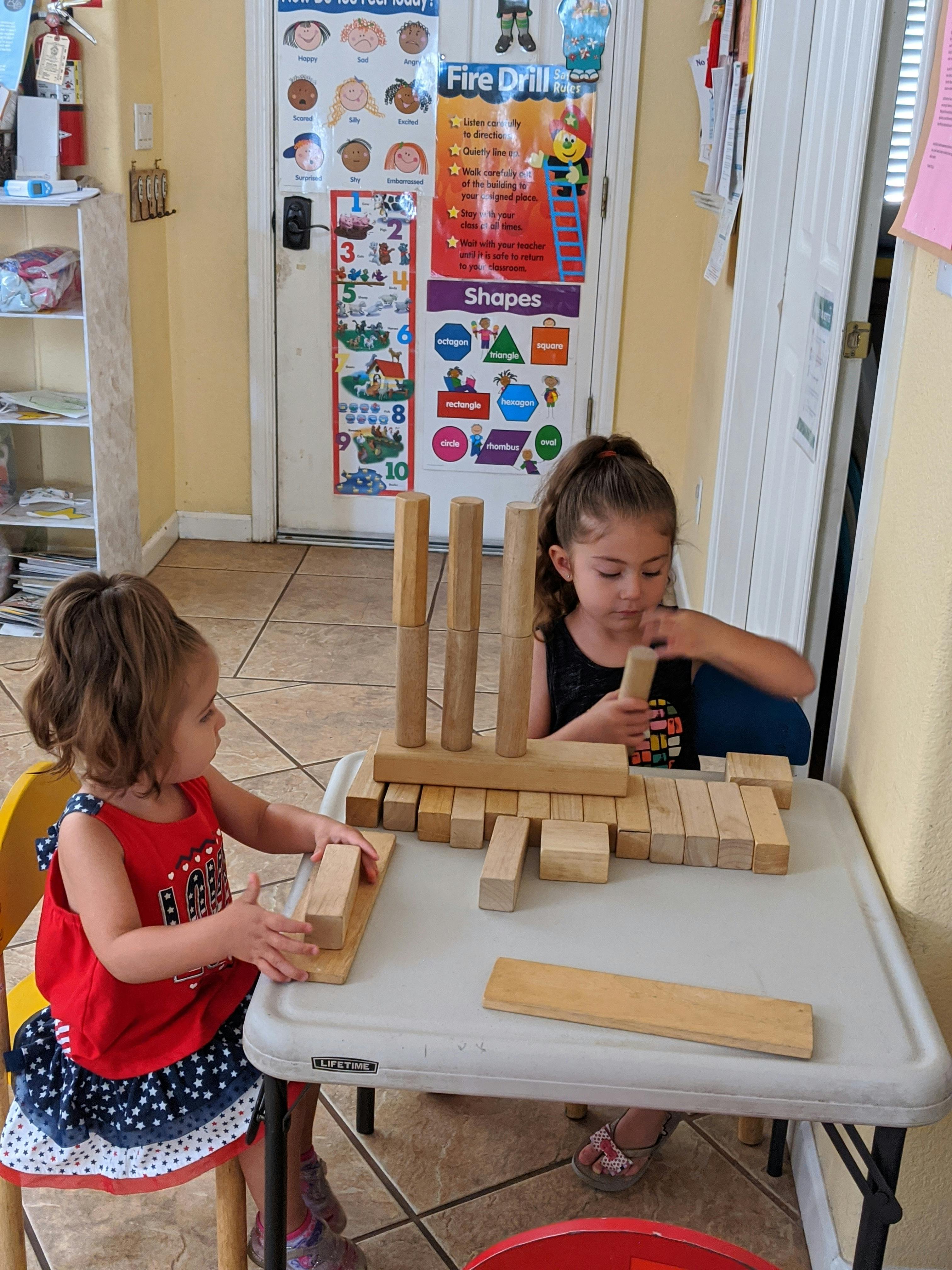 Two children playing with wooden blocks at a table