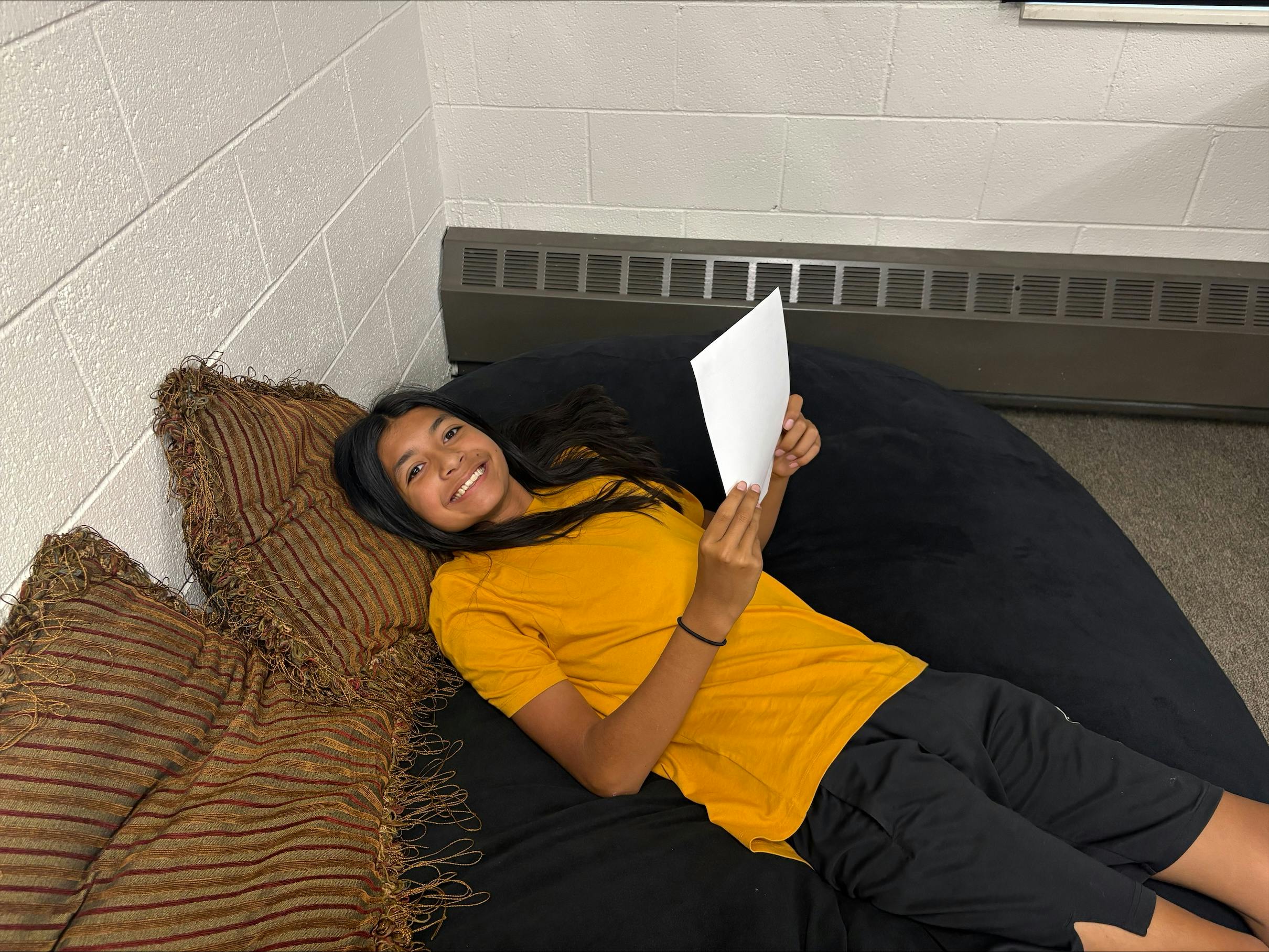 Child lying on a bean bag chair holding a sheet of paper