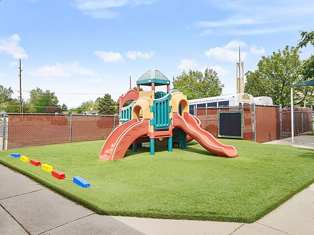 A colorful playground set with slides on artificial turf