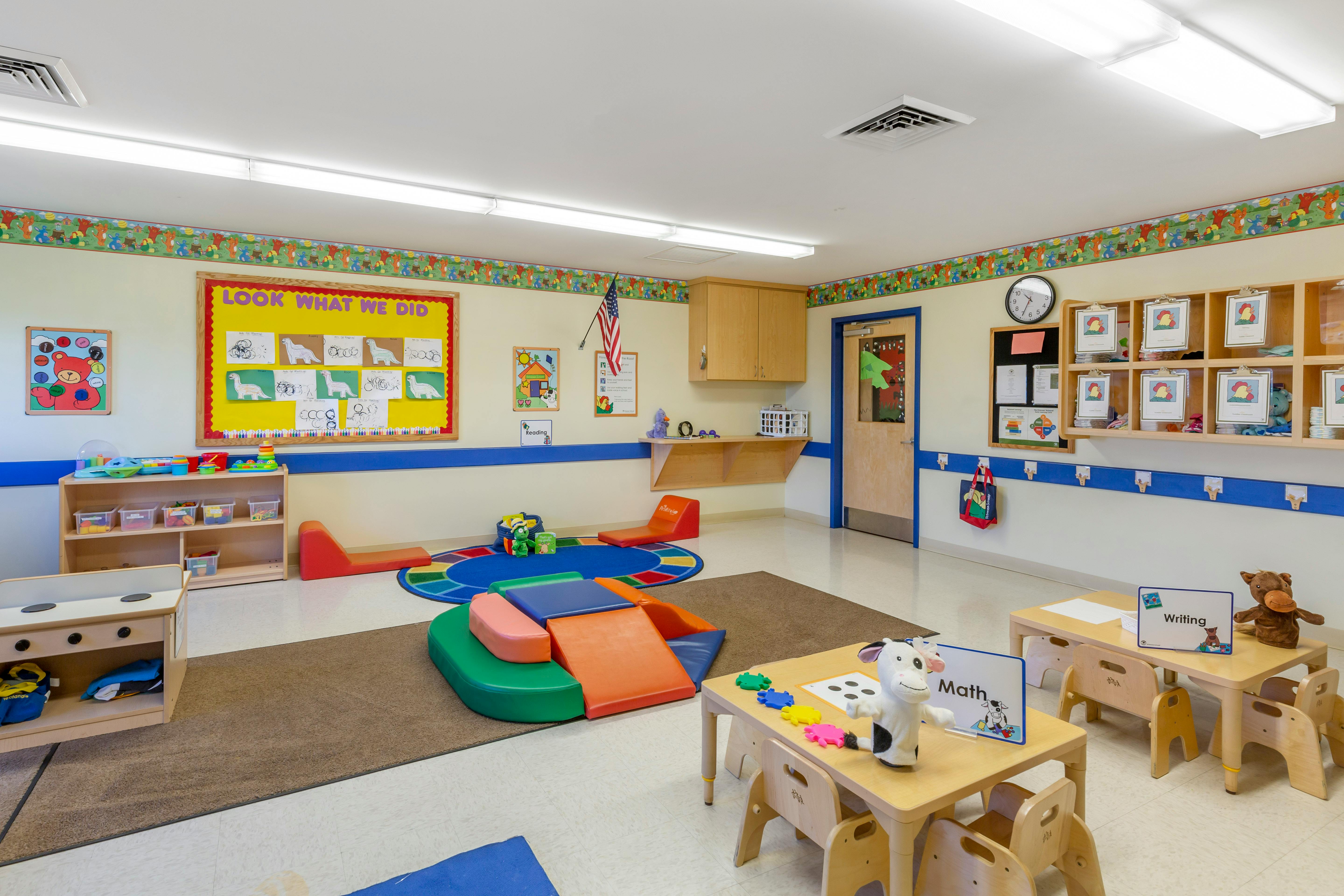 Empty colorful children's classroom with small tables, chairs, and learning materials