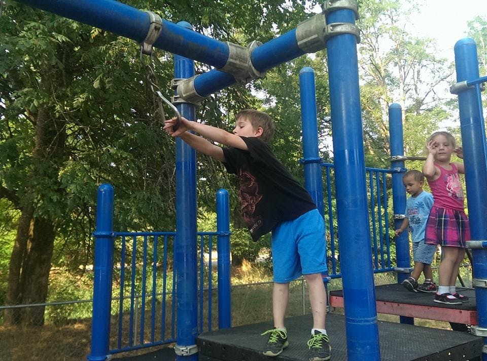 Child on playground equipment pulling a rope