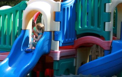 Child on a blue slide on a playground structure