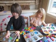 Two children playing with colorful letters and muffin tins