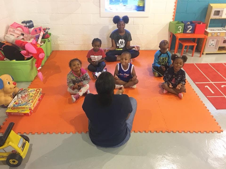 Adult and children sitting on floor in a classroom